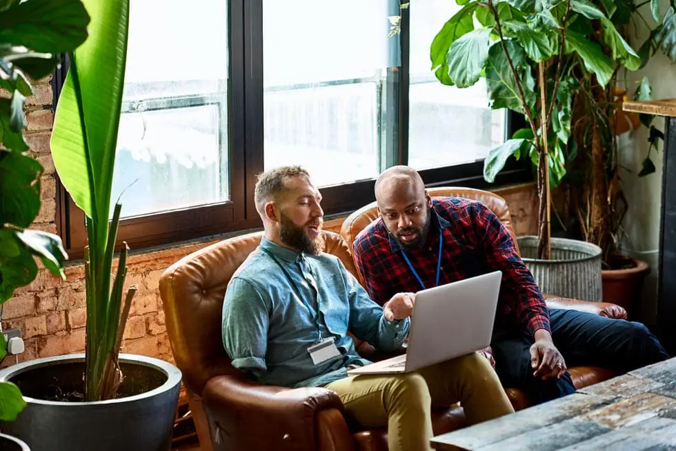 Man using laptop in cafe with business colleague