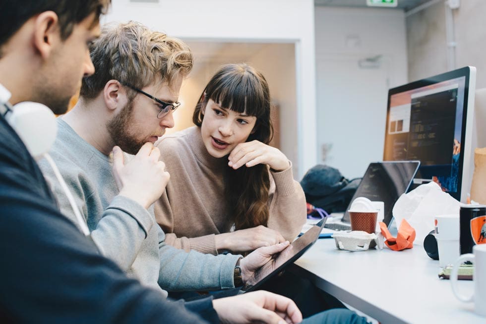 Male and female computer programmers discussing over digital tablet at desk in office